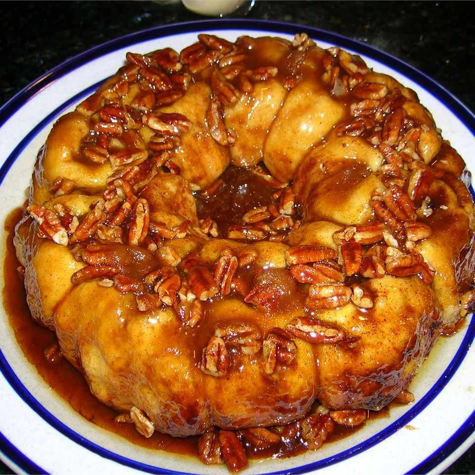 “Bundt pan of pull-apart sticky buns topped with chopped walnuts and caramel glaze.