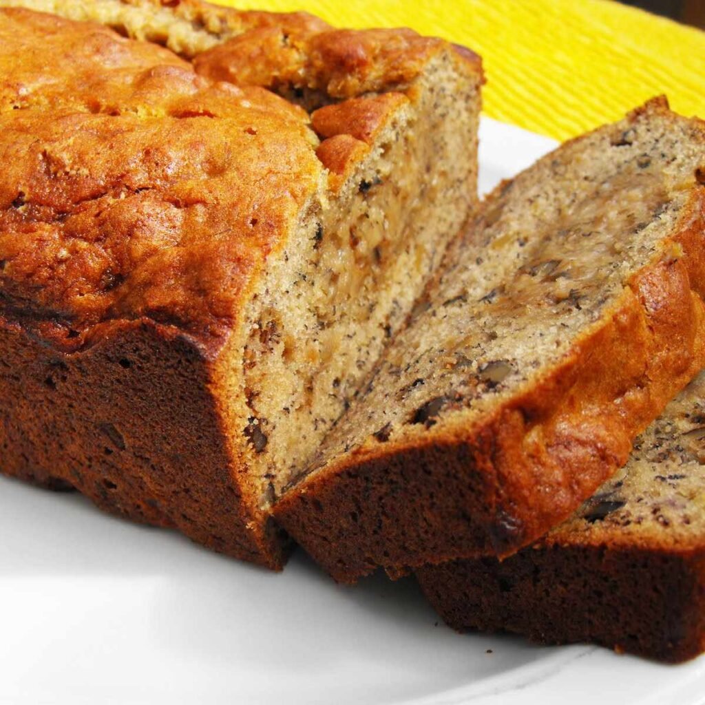 Loaf of banana nut bread with golden-brown crust and visible nut pieces.”