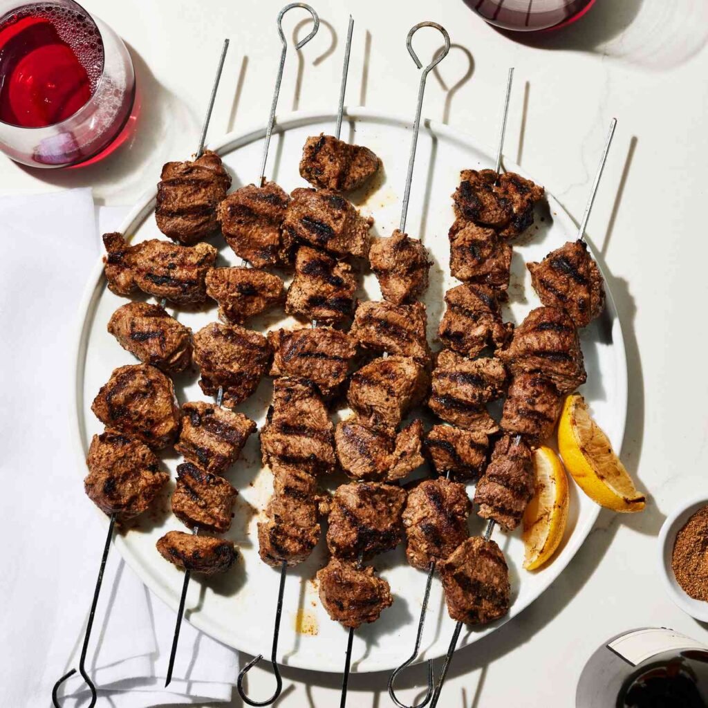 Juicy brown boti pieces on metal skewers, showcasing a deep crust from dry spice rub.
