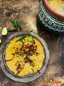  topped with crispy fried onions and garnished with fresh cilantro—served on a rustic wooden table.