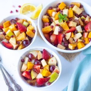“Colorful mixed fruit chaat in a bowl with apple, banana, grapes, pomegranate, garnished with mint.”