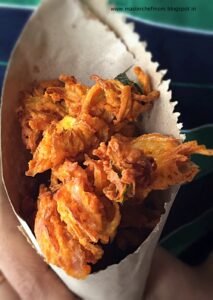 Close-up of golden-brown onion pakoray fritters—thinly sliced onions bound in gram flour batter and deep-fried crisp.