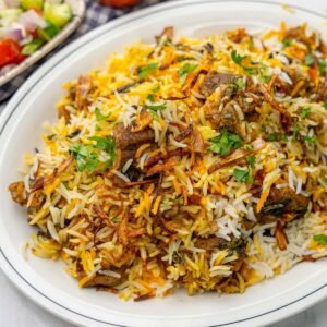 “Pakistani lamb biryani in a ceramic bowl, with golden rice, chunks of lamb, garnished with fresh coriander.”