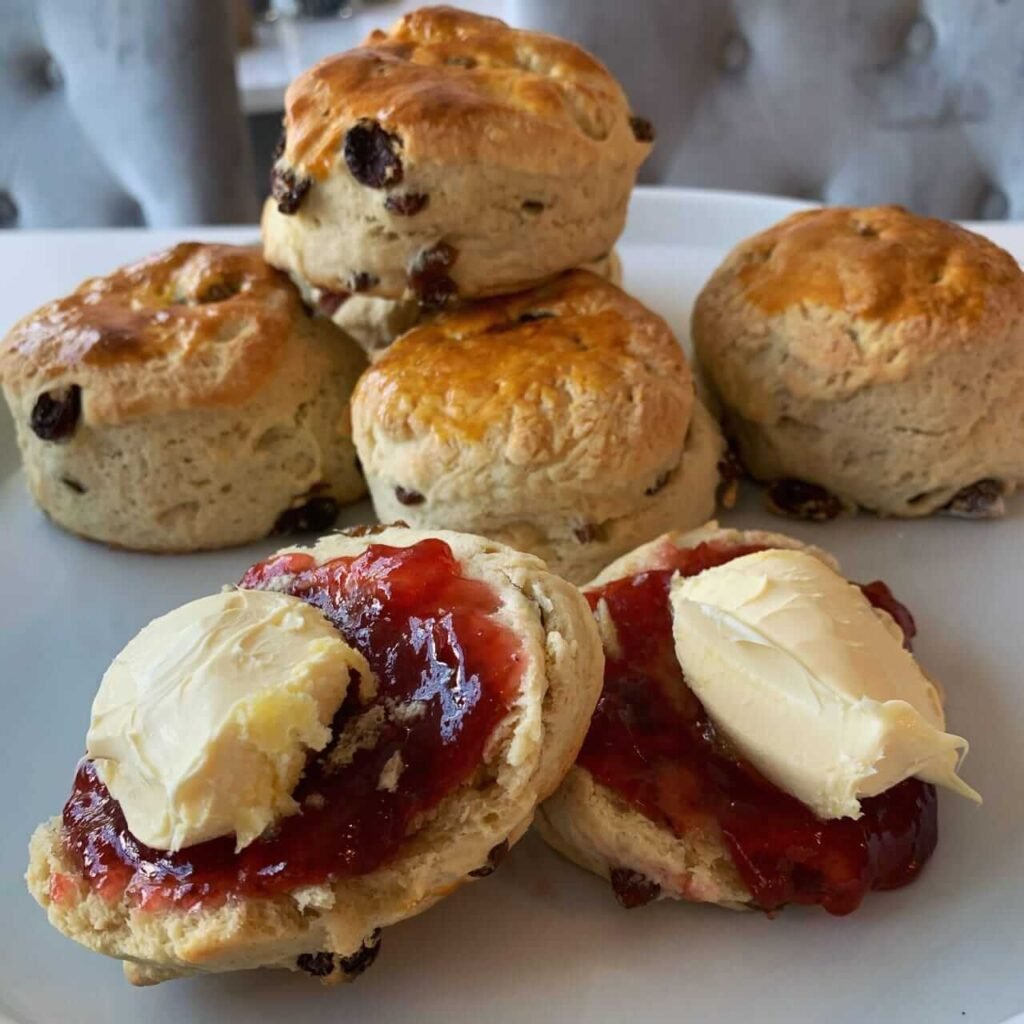 “Three golden‑brown triangular scones stacked in a bowl—flaky and tender inside, crisp crumbly edges, the surface showing slight cracks and a light dusting of flour.”
