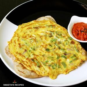 A golden-brown egg paratha on a white plate, topped with fresh green herbs alongside red chutney in a small bowl — showcasing its crisp edges and fluffy texture.