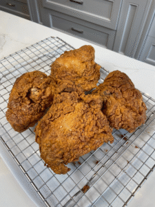 Crispy, deep-fried chicken drumsticks and thighs with an even golden crust, arranged on a cooling rack.”