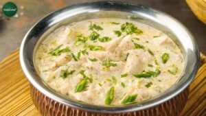 A close-up bowl of butter chicken, featuring tender chicken pieces swimming in a velvety tomato–cream gravy, topped with fresh green cilantro.