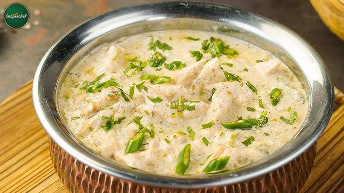 A close-up bowl of butter chicken, featuring tender chicken pieces swimming in a velvety tomato–cream gravy, topped with fresh green cilantro.