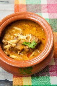 “Traditional kunna served in a clay pot with naan