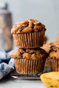 “Creamy peanut butter banana muffins arranged on a plate, topped with banana slices”