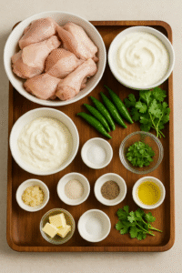 Raw ingredients for creamy chicken white karahi including chicken, yogurt, cream, and spices laid out on a kitchen counter.