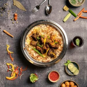 Beef slices coated with yogurt, papaya, and traditional Bihari spices in a steel mixing bowl.