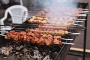 Close-up of juicy beef skewers sizzling on a charcoal grill, with golden brown edges and smoky aroma.